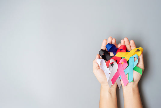 Cancer ribbons being held against a plain background.