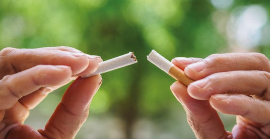 close up of hands breaking a cigarette in half 