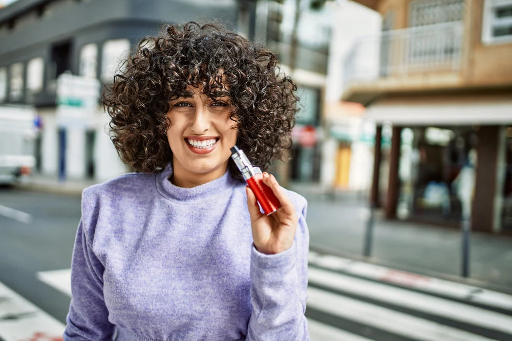 Woman holding a red vape device on a city street