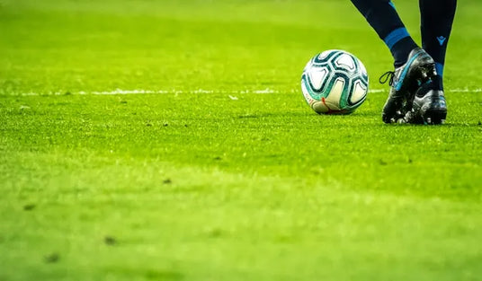Football on a pitch with feet